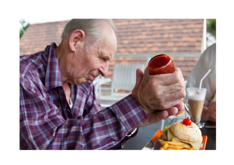 An elderly man applying force to a ketchup bottle, demonstrating Newton's First Law where an object at rest (the ketchup) stays at rest until acted upon by an external force.