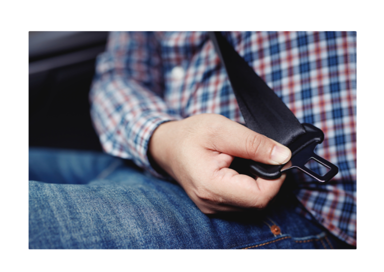 A person fastening a seatbelt in a car, demonstrating Newton's First Law where an object in motion will continue in motion unless acted upon by an external force.